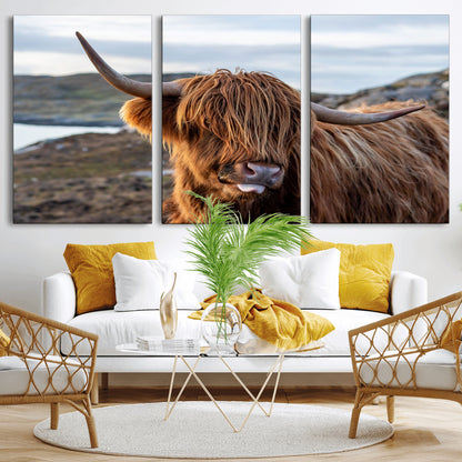 71222-MGV-CV-36X24-A playful Highland cow with shaggy fur sticks out its tongue, set against a rugged landscape — perfect for quirky home or office