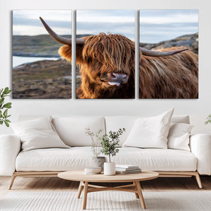 71222-MGV-CV-36X24-A playful Highland cow with shaggy fur sticks out its tongue, set against a rugged landscape — perfect for quirky home or office